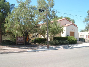 Photo of Socorro church taken from across McCuthcheon Avenue. White adobe building with Spanish tile roof.